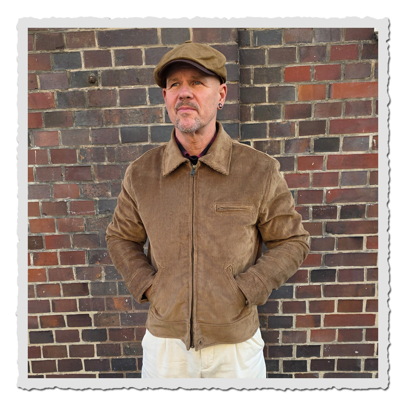 Mann vor Ziegelwand trägt Pike Brothers 1932 Roadster Jacket Light Brass Cord – klassische Cordjacke im Vintage-Stil